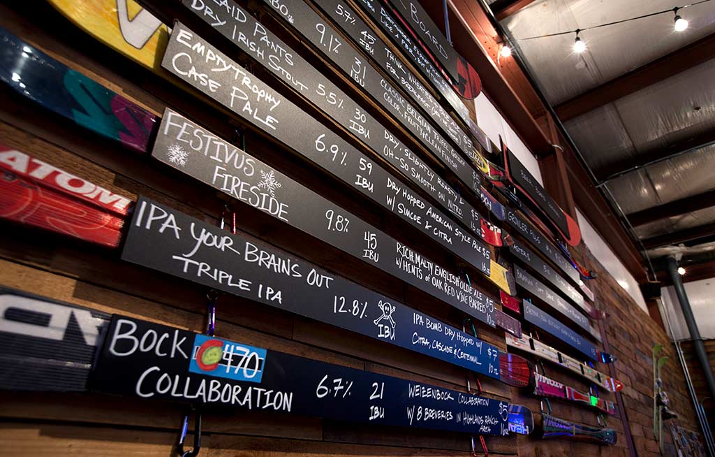 skis hanging on wall with beer names written in chalk